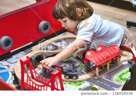 A cute white Caucasian boy playing with a toy train set in a day-care centre A cute white Caucasian boy playing with a toy train set in a day-care centre 136058556