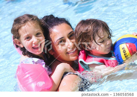 A closeup shot of a cheerful white Caucasian family in the swimming pool - mother, son and daughter enjoying summer 136058568