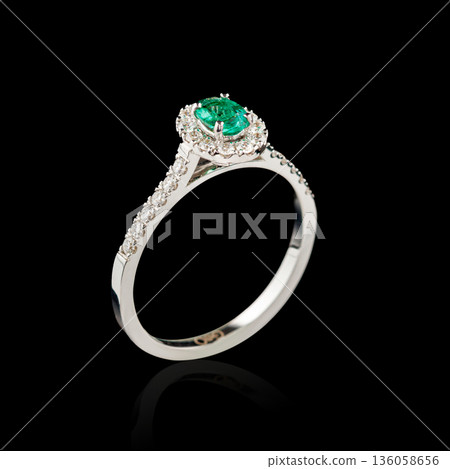 Beautiful white gold ring with diamonds and emerald on a black background Beautiful white gold ring with diamonds and emerald on a black background 136058656