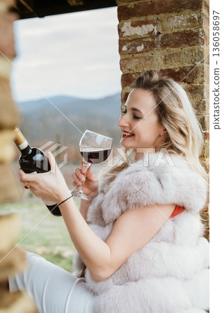 Woman Enjoying Red Wine Outdoors in Winter Attire 136058697