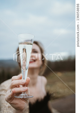 Woman Holding Champagne Glass Cheerfully Outdoors Woman Holding Champagne Glass Cheerfully Outdoors 136058698