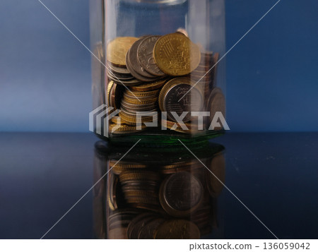Various coins in a glass jar, which typically represents savings or wealth accumulation. Various coins in a glass jar, which typically represents savings or wealth accumulation. 136059042