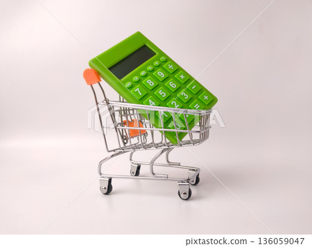 Miniature shopping cart holding a small, bright green calculator. Miniature shopping cart holding a small, bright green calculator. 136059047