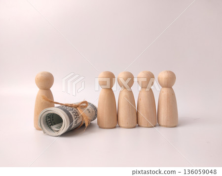 Wooden figures and a roll of hundred-dollar bills, often used to symbolize financial growth or inequality. Wooden figures and a roll of hundred-dollar bills, often used to symbolize financial growth or inequality. 136059048