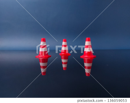 The items shown in the image are miniature traffic cones with reflection on a blue background. 136059053