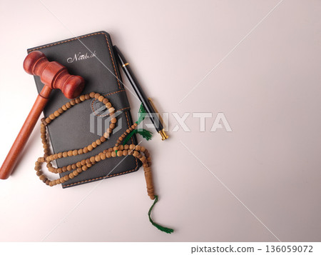 Wooden gavel, prayer beads (tasbih), and a notebook,represent the concept of Islamic law or Sharia. 136059072