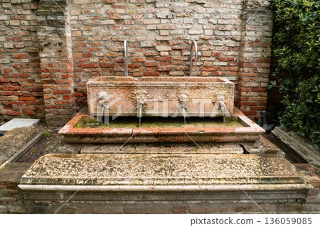 Old stone fountain with lion head spouts and brick wall, Venice Italy Old stone fountain with lion head spouts and brick wall, Venice Italy 136059085