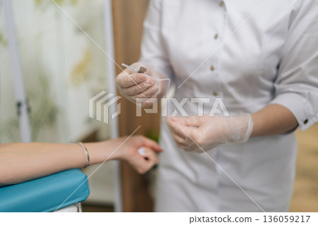 Close-up cropped shot of unrecognizable patient receiving blood test preparation from medical professional, getting blood sample drawn for laboratory analysis in clinical healthcare environment. 136059217