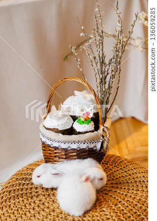 Easter basket with kulich cakes and white bunnies on cozy spring background Easter basket with kulich cakes and white bunnies on cozy spring background 136059285