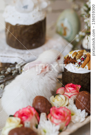 Chocolate Easter eggs with roses and bunny in carton on festive spring table, soft bokeh 136059300