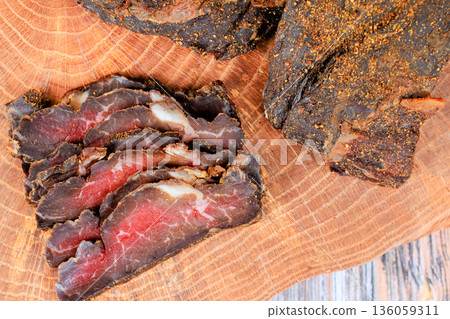 Cured meat is arranged on wooden surface with whole beef meat piece. 136059311