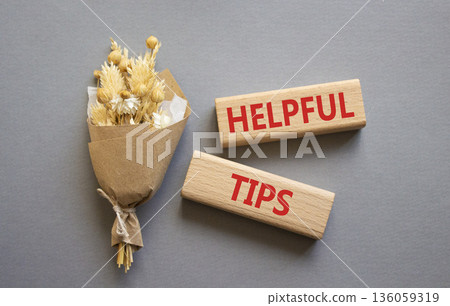 Helpful tips symbol. Wooden blocks with words Helpful tips. Beautiful grey background with bouquet of flowers. Business and Helpful tips concept. Copy space. 136059319