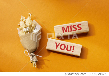 Miss you symbol. Concept word Miss you on wooden blocks. Beautiful orange background with bouquet of flowers. Business and Miss you concept. Copy space 136059323
