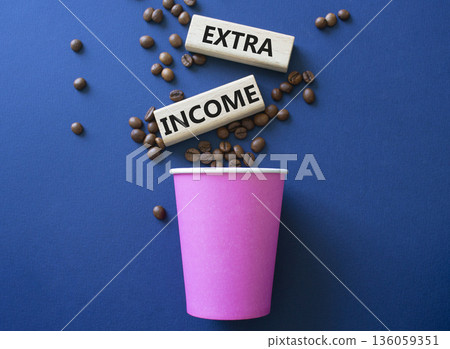 Extra Income symbol. Concept words Extra Income on beautiful wooden picture frame. Beautiful deep blue background with coffee cup and coffee beans. Business and Extra Income concept. Copy space. Extra Income symbol. Concept words Extra Income on beautiful wooden picture frame. Beautiful deep blue background with coffee cup and coffee beans. Business and Extra Income concept. Copy space. 136059351