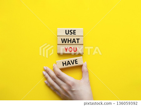 Use what you Have symbol. Concept words Use what you Have on wooden blocks. Beautiful bright yellow background. Businessman hand. Business and Use what you Have concept. Copy space. 136059392