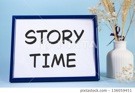 Story Time symbol. Concept words Story Time on beautiful wooden picture frame. Beautiful light blue background with flower vase. Business and Story Time concept. Copy space. 136059451