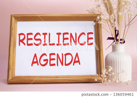 Resilience agenda symbol. Concept words Resilience agenda on beautiful wooden picture frame. Beautiful pink background with flower vase. Business and Resilience agenda concept. Copy space. Resilience agenda symbol. Concept words Resilience agenda on beautiful wooden picture frame. Beautiful pink background with flower vase. Business and Resilience agenda concept. Copy space. 136059461
