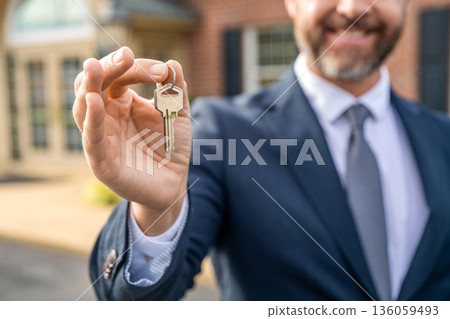 Realtor in suit hold key outdoor. Real estate agent showing house for sale. Property insurance. Real estate market. Selective focus. Broker man. House insurance. Realtor offering new home 136059493