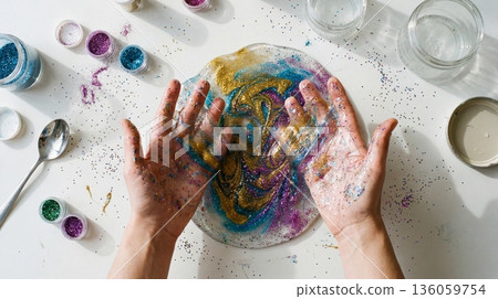 Hands mixing colorful slime with glitter on white table. Creative sensory play and anti-stress hobby for adults. Messy fun art craft project concept. 136059754