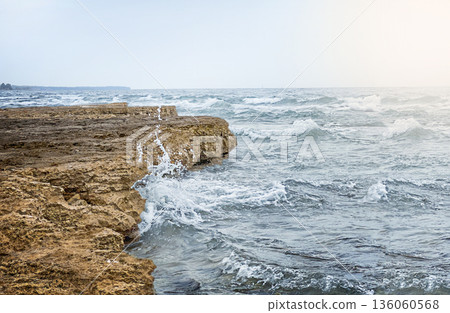 Rocky coastline with waves crashing against the shore. Rocky coastline with waves crashing against the shore. 136060568