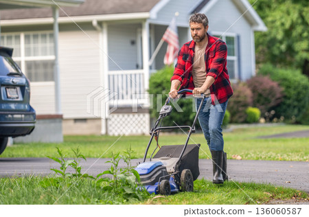 Lawnmower mow green grass. Man gardener cut the grass. Garden care. Electric lawn mower. Landscape design. Lawn mower landscaping. Backyard grass maintenance. Hispanic gardener. Copy space banner 136060587