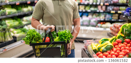 Man shopping at grocery store. Healthy lifestyle. Organic food basket. Man in grocery store. Man shopping with vegetable basket in supermarket. Grocery consumer. Neighborhood grocery Man shopping at grocery store. Healthy lifestyle. Organic food basket. Man in grocery store. Man shopping with vegetable basket in supermarket. Grocery consumer. Neighborhood grocery 136061582