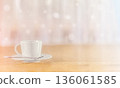 Mixed background. A white coffee cup on a saucer with a spoon rests on a wooden table.  136061585
