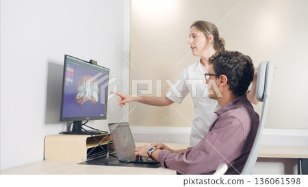 Dentist explaining 3d teeth model to patient Dentist explaining 3d teeth model to patient 136061598