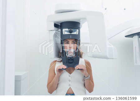 Woman undertaking panoramic dental x-ray scan procedure 136061599