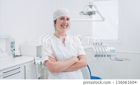 Female dentist smiling with crossed arms in dental clinic 136061604