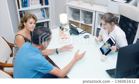 Dentist explaining treatment plan to senior couple Dentist explaining treatment plan to senior couple 136061612