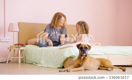 Mother and daughter reading story with boxer dog Mother and daughter reading story with boxer dog 136061657