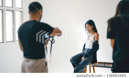 Photographer taking pictures of model posing in studio Photographer taking pictures of model posing in studio 136061669