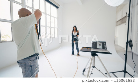 Photographer taking pictures of model in professional studio 136061688