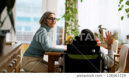 Woman talking with man living with a disability at home Woman talking with man living with a disability at home 136061726