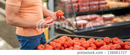 Man shopping tomato in grocery store. Healthy lifestyle. Fresh food store. Man in grocery store. Man shopping in vegetable supermarket. Grocery consumer with tomato, cropped view. Copy space Man shopping tomato in grocery store. Healthy lifestyle. Fresh food store. Man in grocery store. Man shopping in vegetable supermarket. Grocery consumer with tomato, cropped view. Copy space 136061727