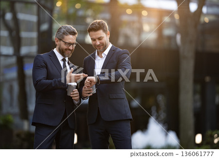 Businesspeople check time with coffee cup. Colleague have business meeting. Business of businesspeople. Coffee break. Businesspeople outdoor. Business colleague at coffee break. Punctuality Businesspeople check time with coffee cup. Colleague have business meeting. Business of businesspeople. Coffee break. Businesspeople outdoor. Business colleague at coffee break. Punctuality 136061777