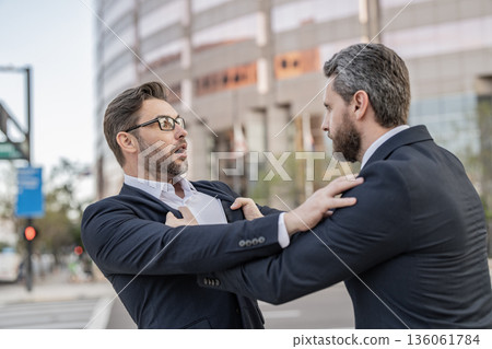 Two businessmen conflicting at fight outdoor. Businessmen having conflict in business. Conflict between boss and employee. Fight aggression. Angry businessmen threatening. Business conflict Two businessmen conflicting at fight outdoor. Businessmen having conflict in business. Conflict between boss and employee. Fight aggression. Angry businessmen threatening. Business conflict 136061784
