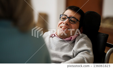 Man with physical disability smiling, enjoying conversation 136061823