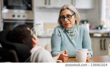Mother providing attentive care to adult son living with physical condition Mother providing attentive care to adult son living with physical condition 136061824