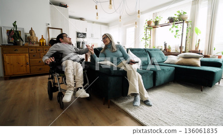 Adult son in wheelchair holding hand of smiling mother Adult son in wheelchair holding hand of smiling mother 136061835