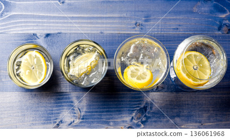 Detox after party. Health care concept. What to drink on christmas party. Cocktail glasses with water and slice of lemon on blue wooden surface. Detox drink to feel better. Hangover and detox 136061968