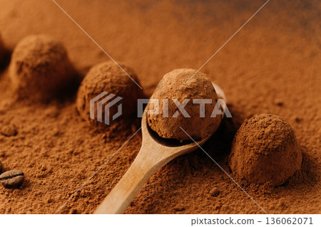 Cocoa truffles on wooden spoon in cocoa powder, closeup Cocoa truffles on wooden spoon in cocoa powder, closeup 136062071