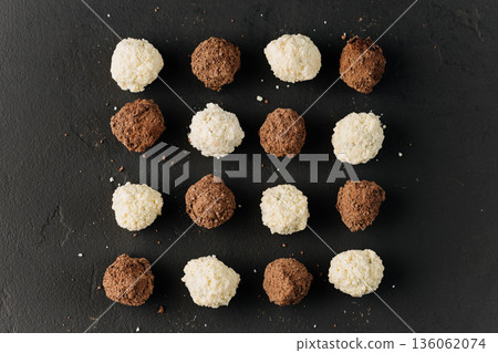 Assorted coconut and cocoa truffles on black slate, flat lay 136062074