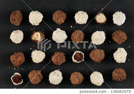 Assorted coconut and cocoa truffles on black slate, flat lay Assorted coconut and cocoa truffles on black slate, flat lay 136062078
