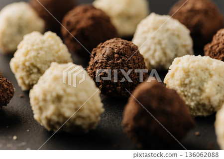 Macro coconut truffle with creamy center and cocoa truffles on dark slate Macro coconut truffle with creamy center and cocoa truffles on dark slate 136062088