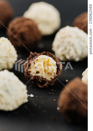 Bitten chocolate truffle with creamy center on dark background, macro dessert 136062089
