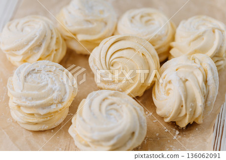 Vanilla zephyr marshmallow rosettes on parchment, soft pastel closeup 136062091