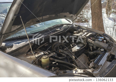 Open car hood showing engine bay in winter outdoors. Concept of vehicle maintenance, breakdown, repair, inspection, and cold weather car problems. Open car hood showing engine bay in winter outdoors. Concept of vehicle maintenance, breakdown, repair, inspection, and cold weather car problems. 136062133