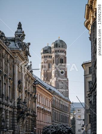 Historic Munich Old Town Street With Cathedral Of Our Dear Lady: Narrow Urban Alley Framing Iconic Twin Domed Church Towers And Traditional Bavarian Architecture 136062368